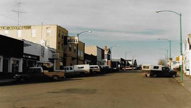 A street with cars parked in front of buildings

Description automatically generated